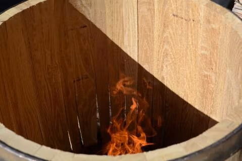 Büttner toastet ein Eichenfass über offener Feuerschale in der Fassherstellung